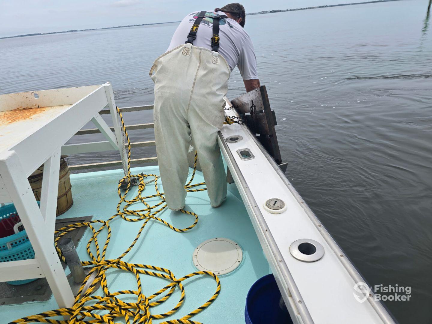 A crew member is preparing equipment on the deck of a fishing boat, showcasing the boat's interior and fishing environment.