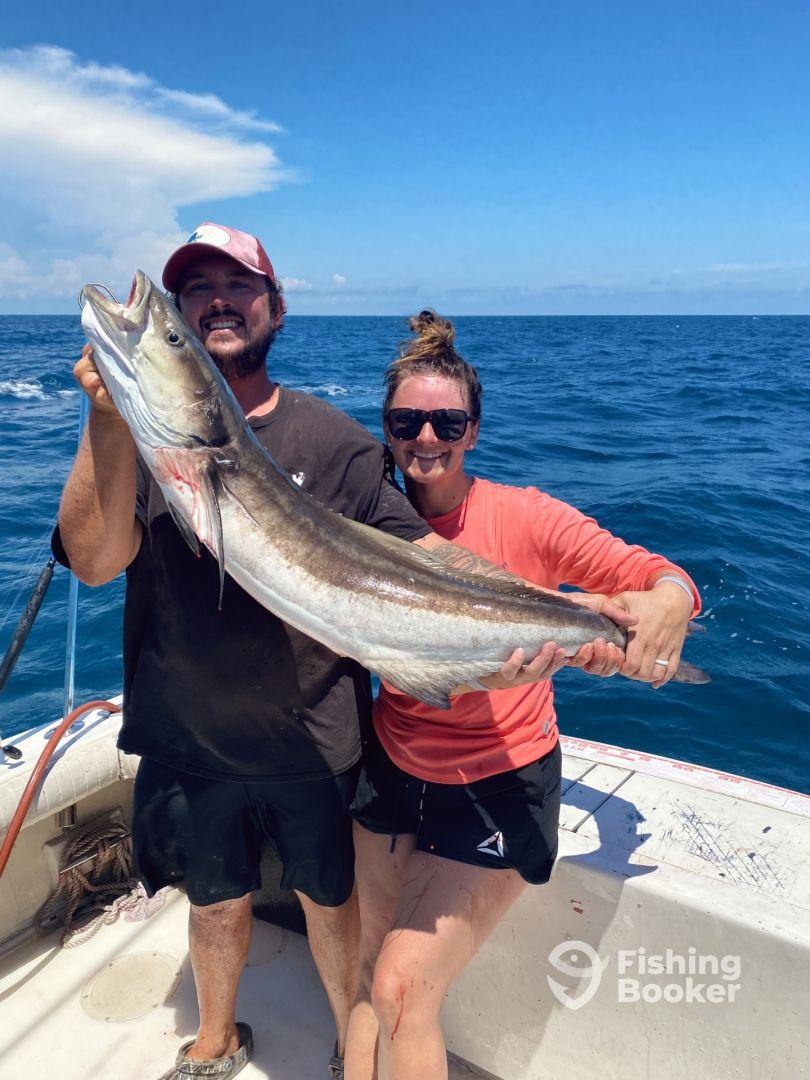 Two anglers proudly displaying a large Cobia caught during a deep-sea fishing trip.