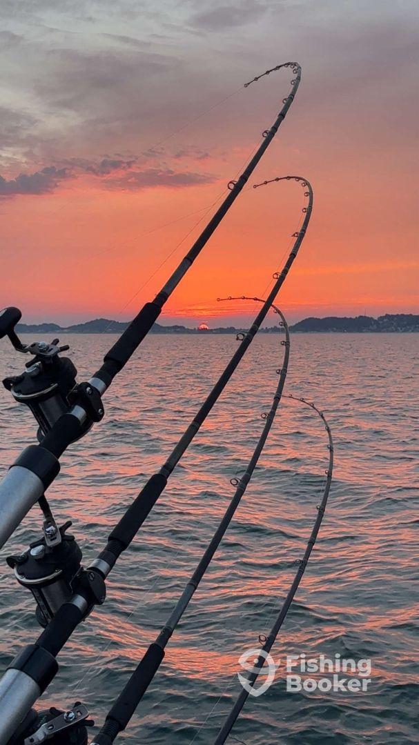 Fishing rods bent under tension against a stunning sunset backdrop, capturing the essence of a serene evening fishing trip.