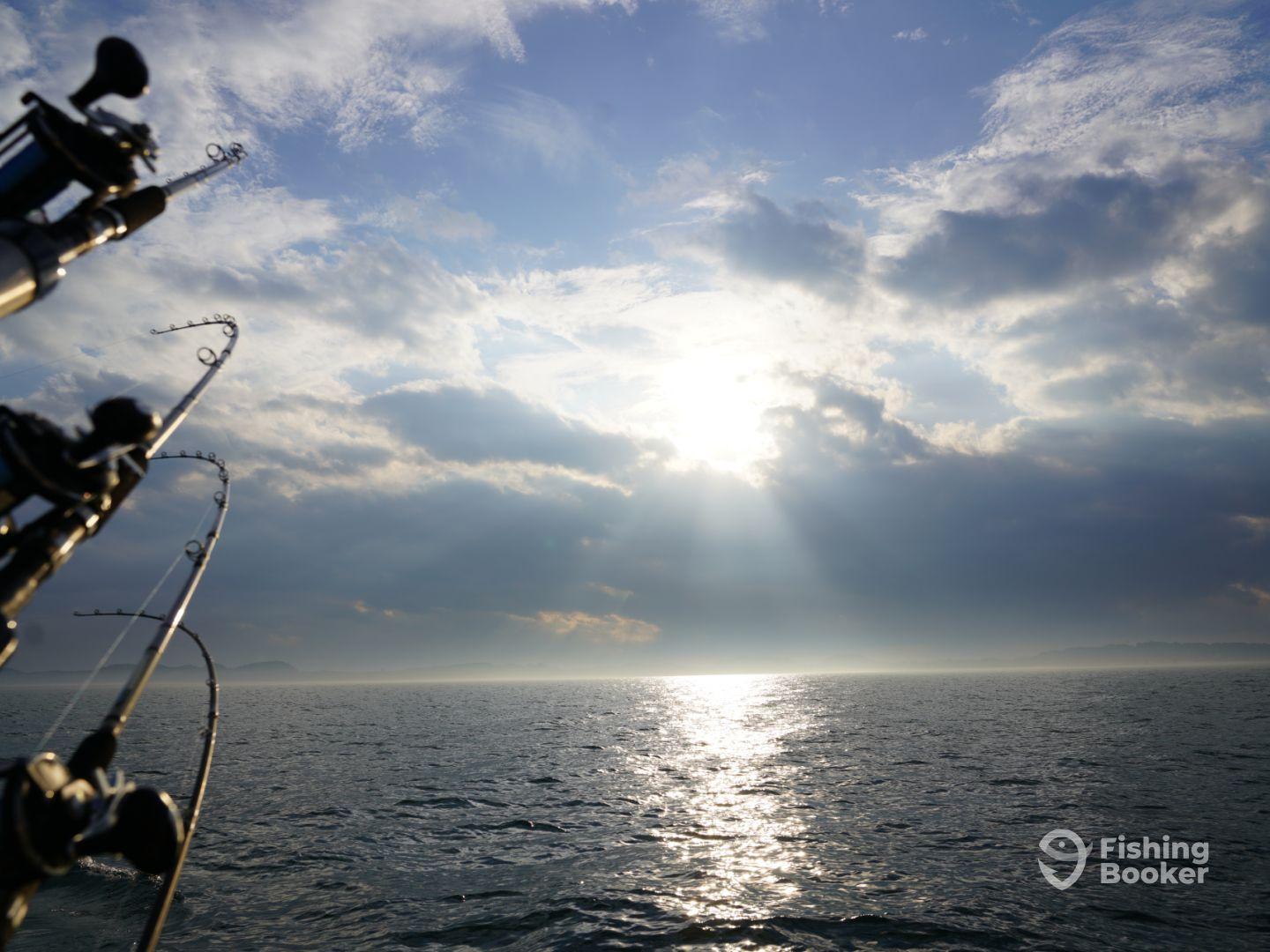 A scenic view of the ocean with fishing rods in the foreground, capturing the serene atmosphere during a fishing trip.