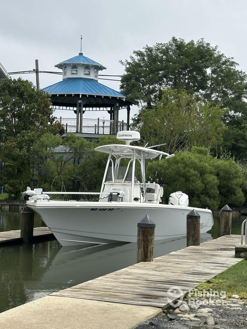 A sleek center console boat docked near a waterfront pavilion, showcasing its modern design and Garmin electronics.