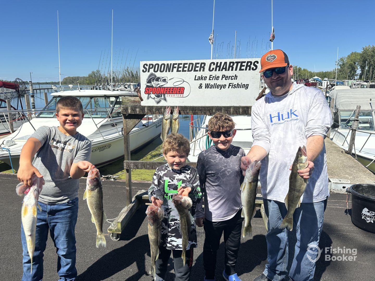 A group of young anglers proudly displaying their catch of Lake Erie Walleye after a successful fishing trip with Spoonfeeder Charters.