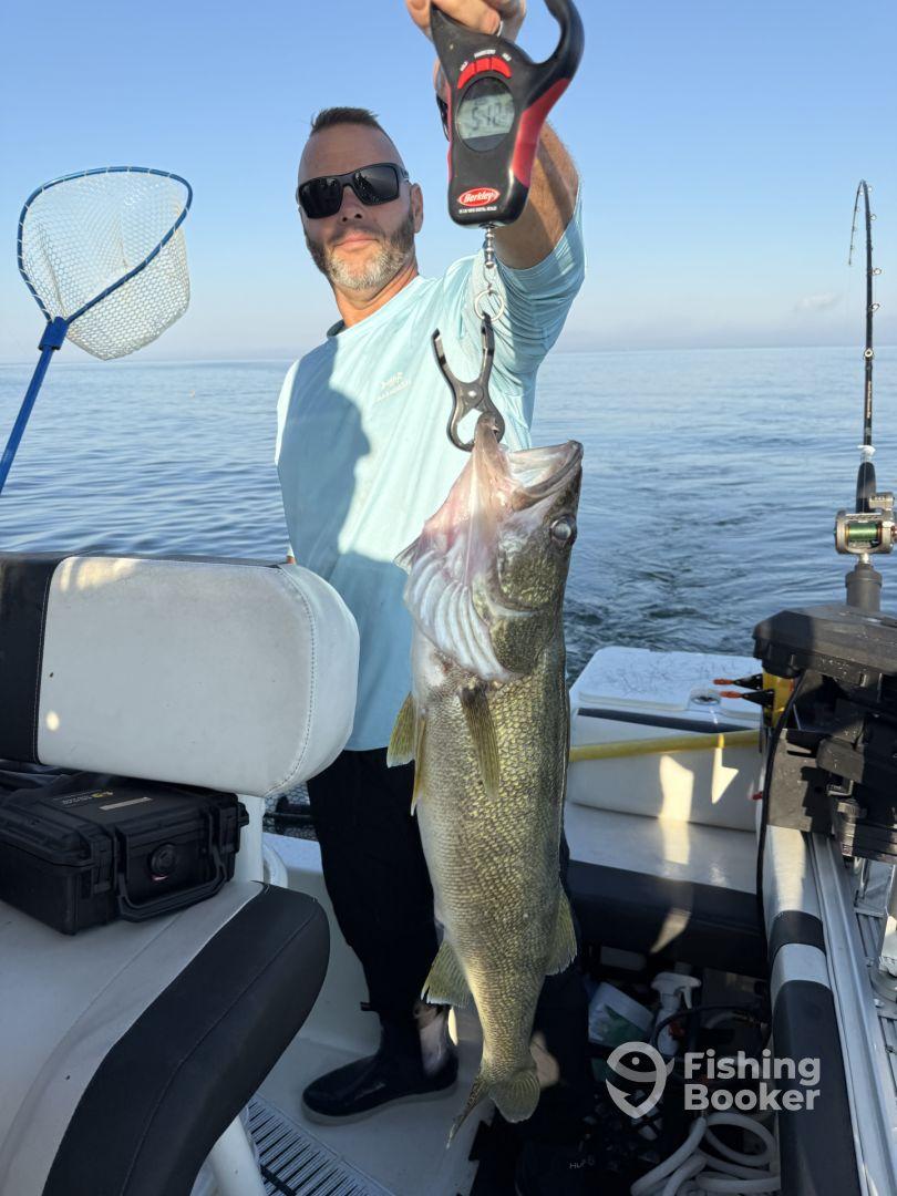 An angler proudly displaying a large Walleye while fishing on a calm lake, showcasing the thrill of a successful catch.