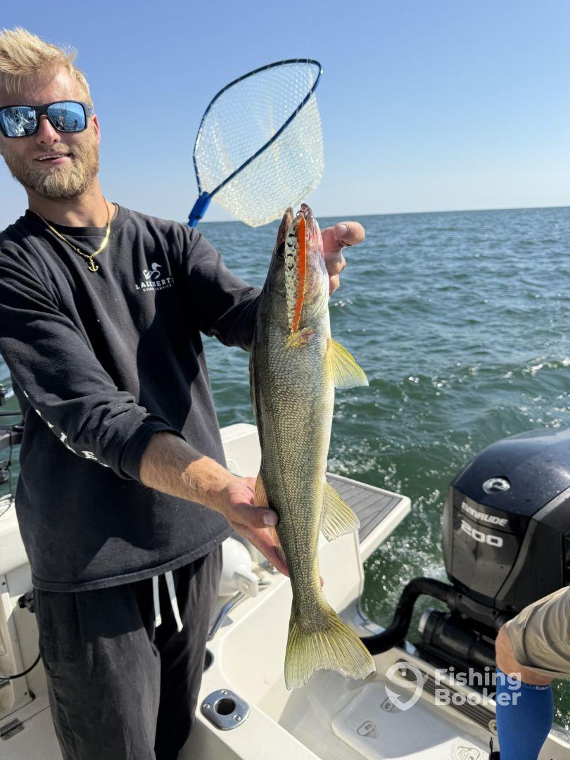 Angler proudly displaying a large Walleye while fishing on a boat, showcasing a successful catch in a sunny environment.