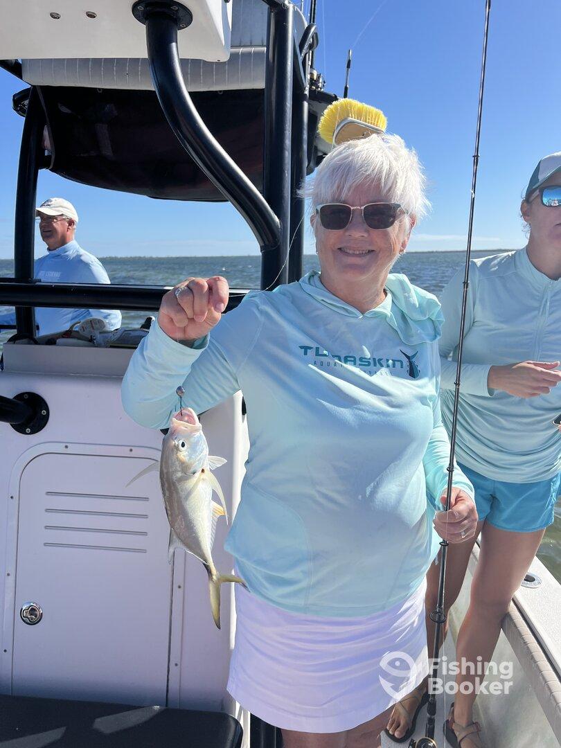 An angler proudly displaying a caught fish while fishing on a boat, enjoying a sunny day on the water.