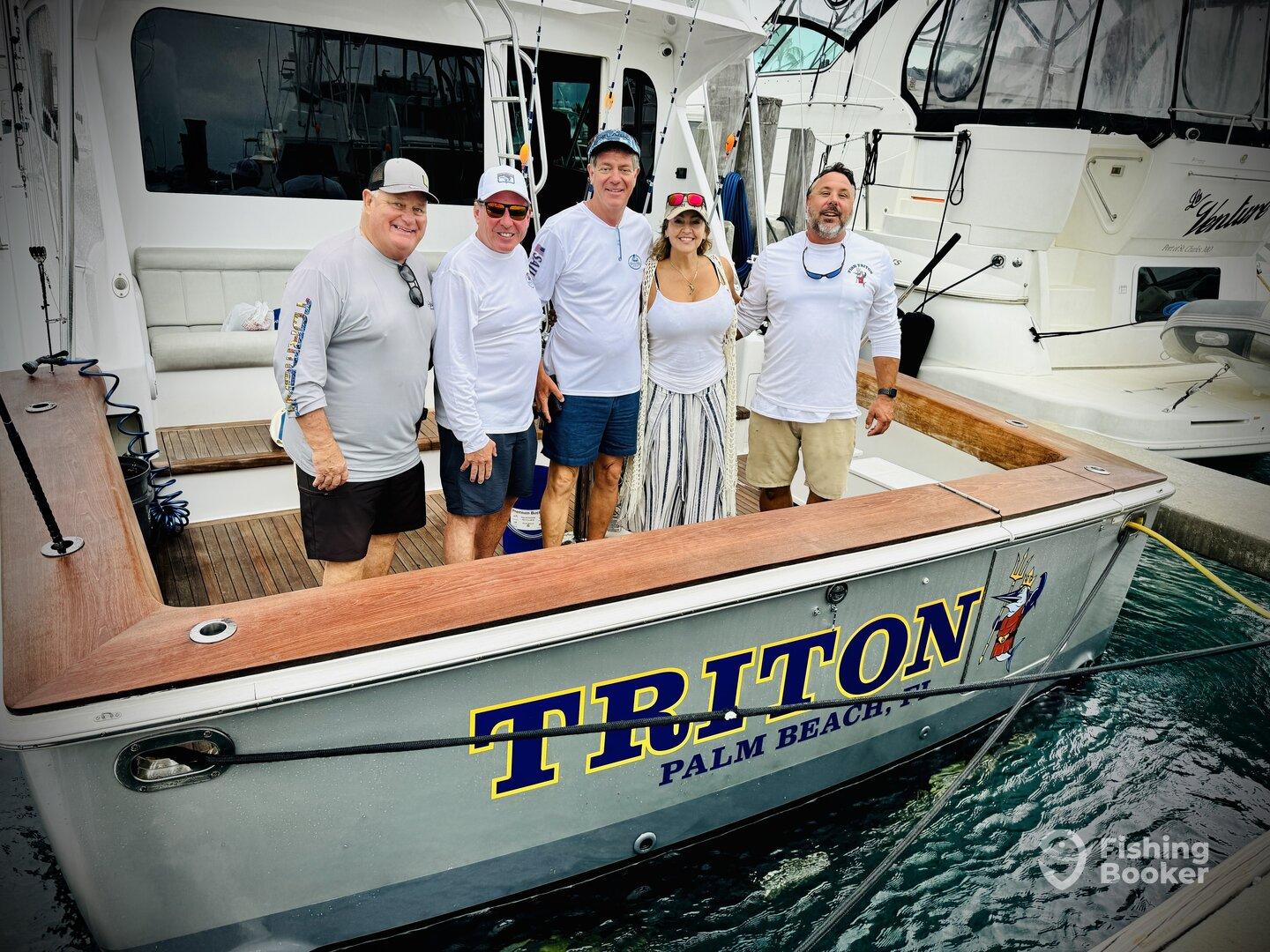 A group of five anglers posing on the deck of the Triton boat, showcasing a fun day of fishing in Palm Beach.