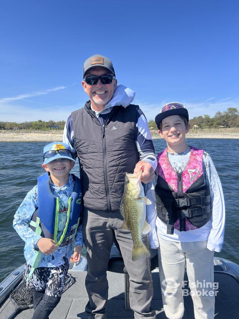A proud family moment on the water with a young angler holding a large Largemouth Bass while fishing together.