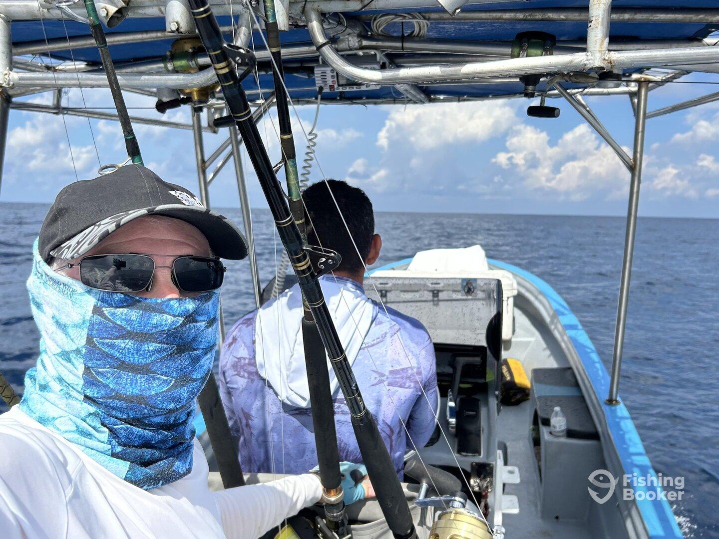 Two anglers aboard a fishing boat, with one at the helm and the other preparing for a fishing adventure in open waters.