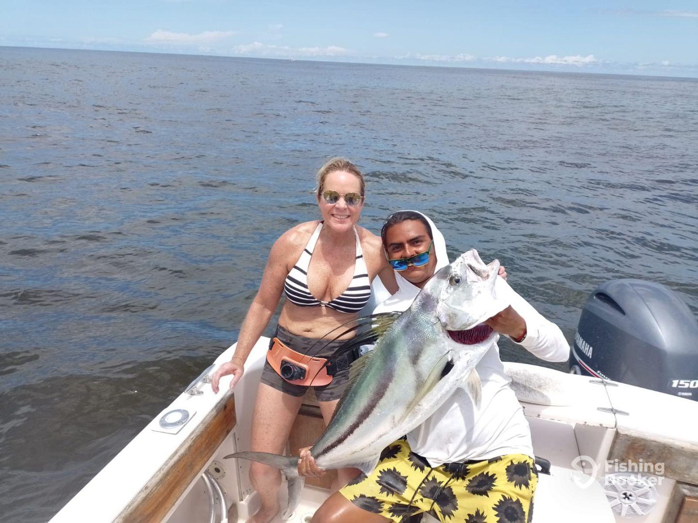 Two anglers proudly displaying a large fish while on a boat in open water, showcasing a successful fishing trip.