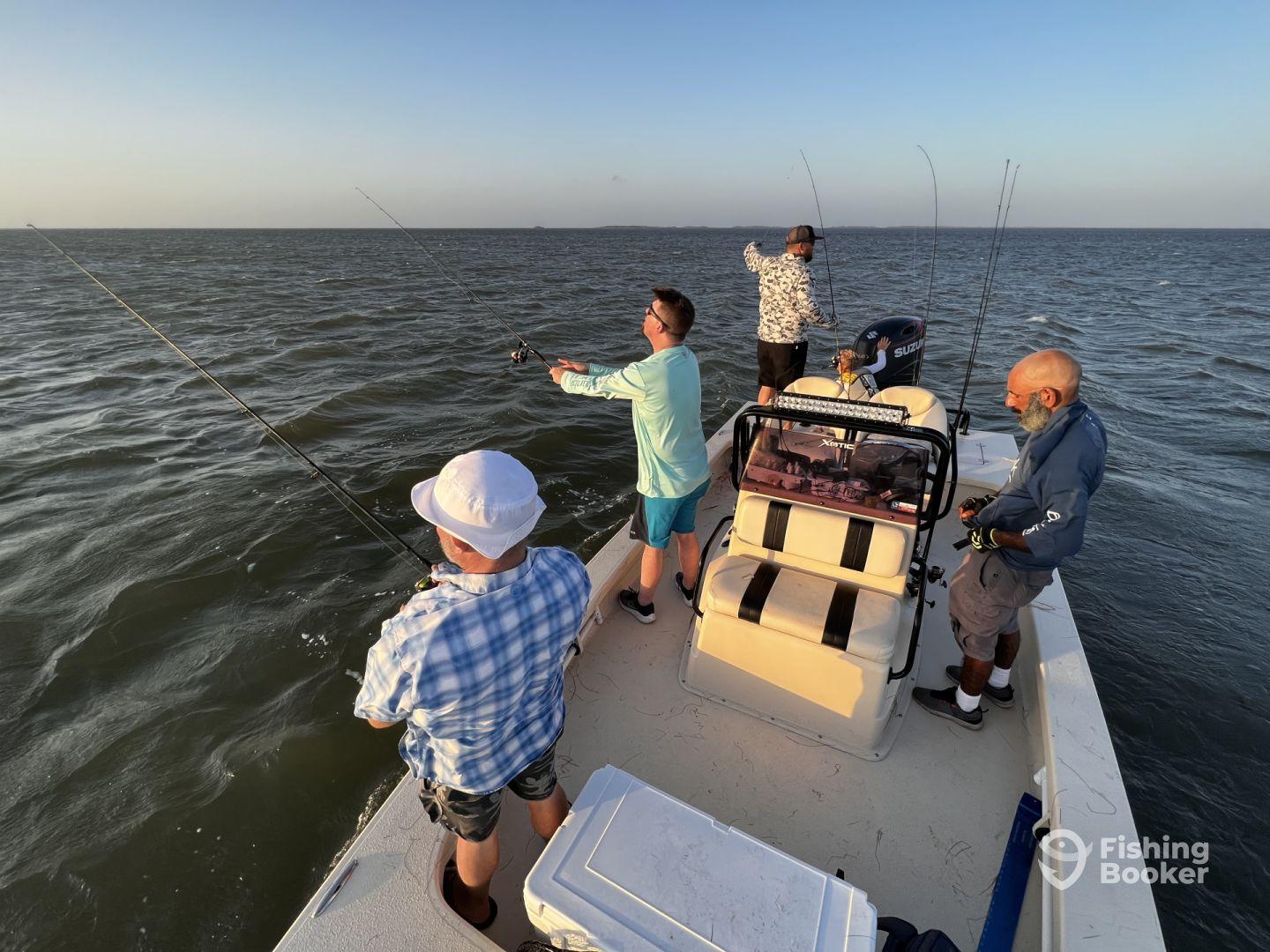 Group of anglers actively fishing on a boat, casting lines into the water during a sunset fishing trip.