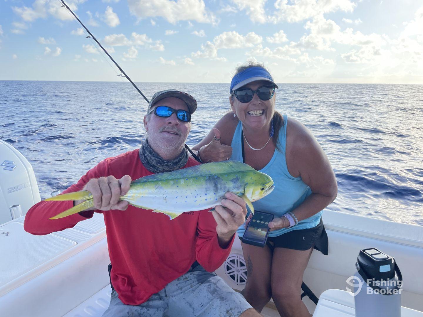Two anglers proudly displaying a vibrant Mahi Mahi while fishing offshore, showcasing a successful day on the water.