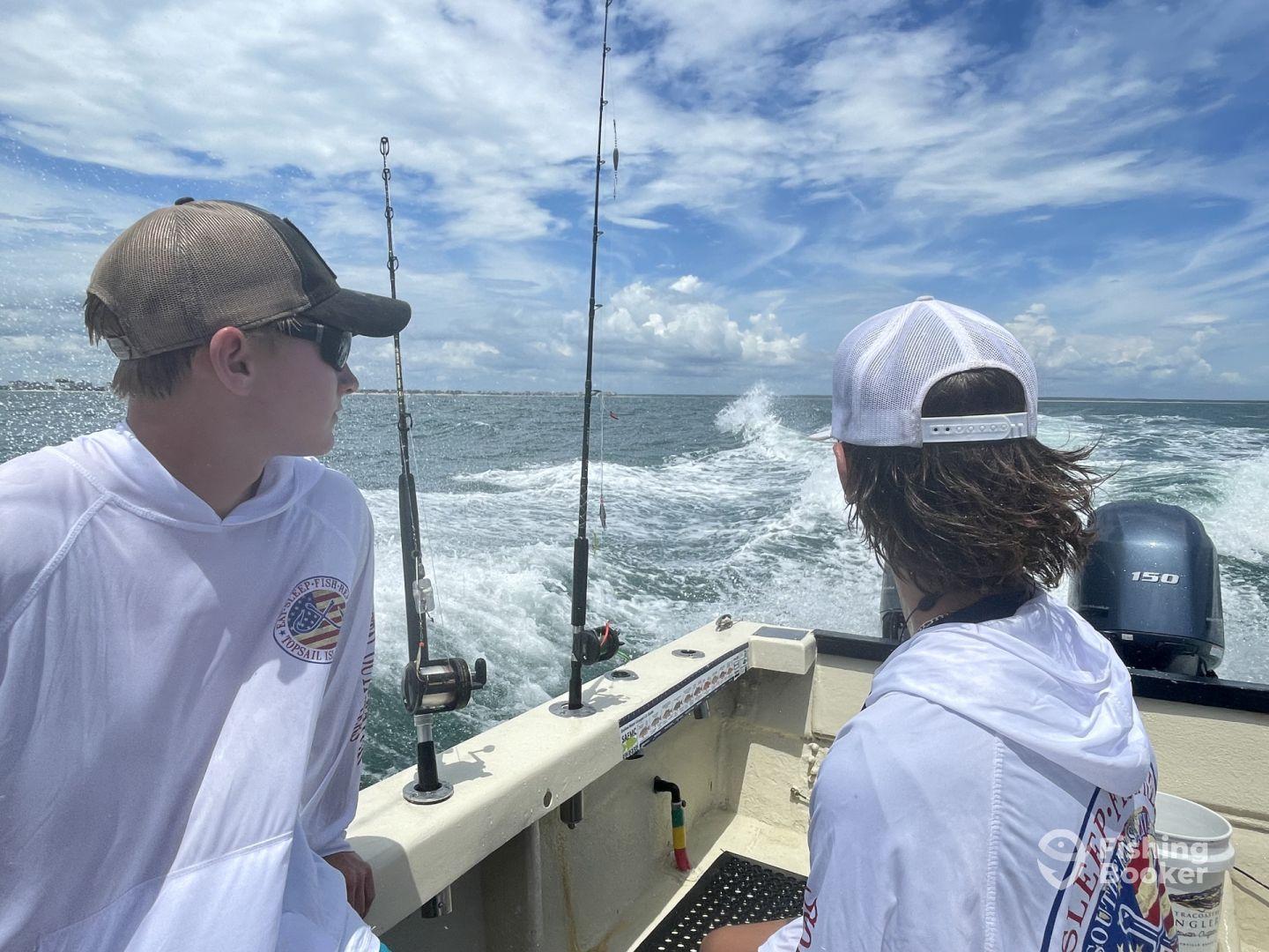 Two young anglers enjoying a day on the water, seated in the boat as they head out for a fishing adventure.