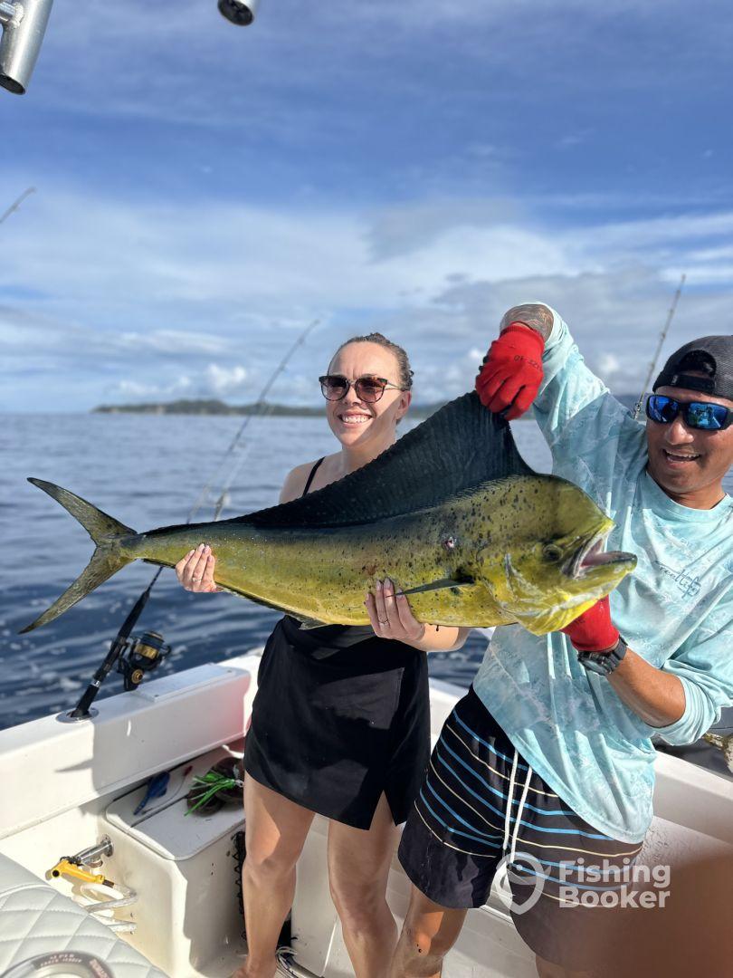 Two anglers proudly displaying a large Mahi Mahi while fishing offshore, showcasing a beautiful day on the water.