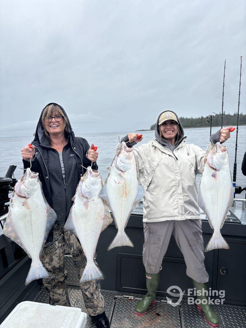 Two anglers proudly displaying their catch of large Halibut while fishing on a boat in a coastal environment.