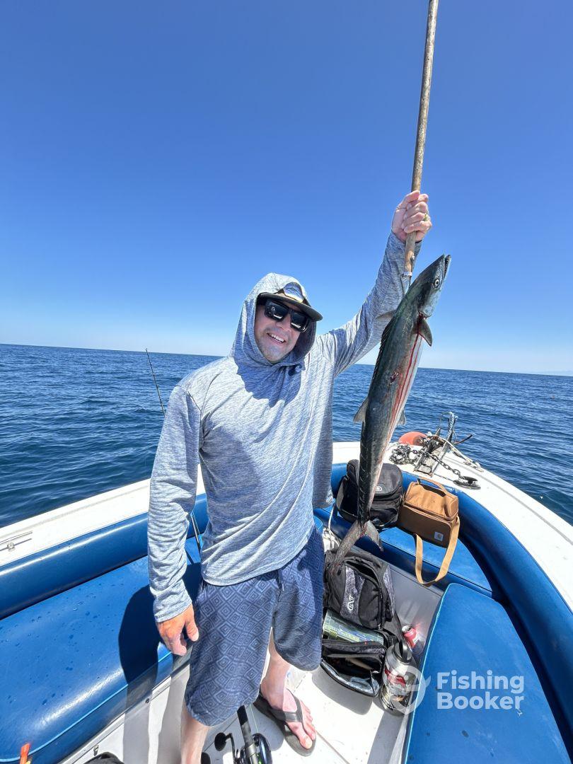 Angler proudly displaying a large fish while aboard a fishing boat in open waters, showcasing a successful day of fishing.