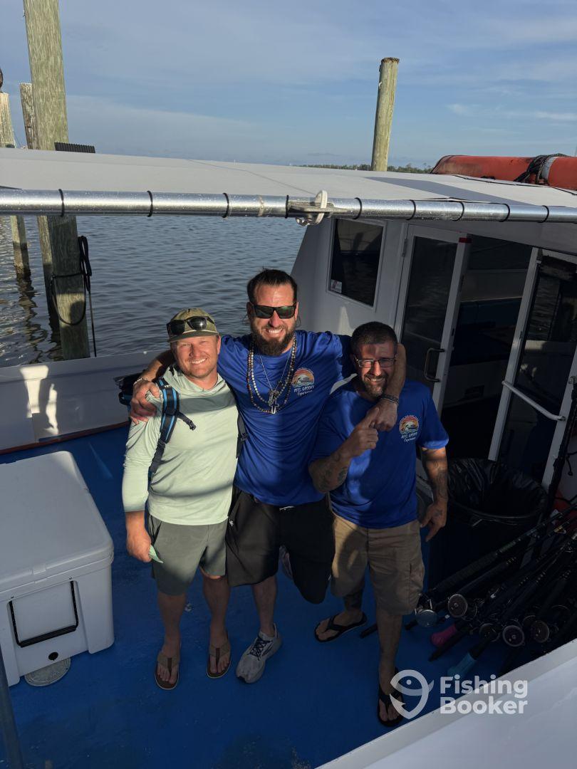 Three anglers posing together inside the boat, showcasing camaraderie before a fishing trip.