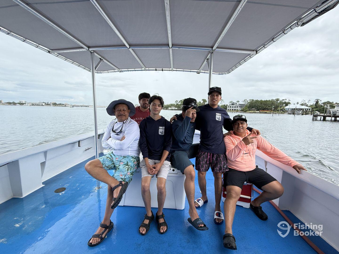 A group of anglers relaxing inside a fishing boat, showcasing a comfortable seating area with a scenic view of the water.