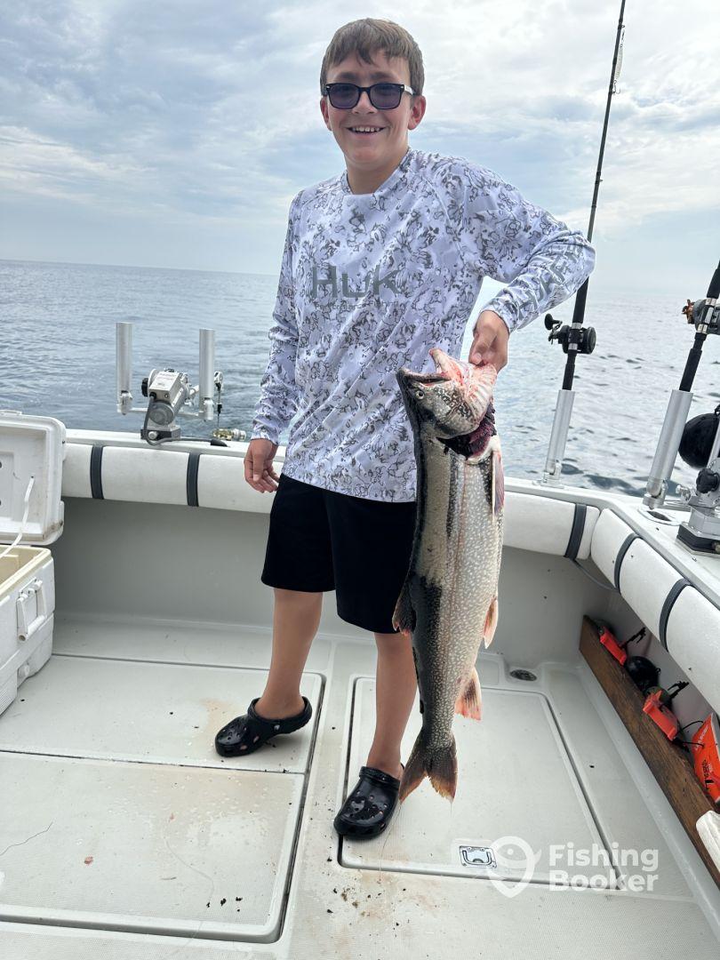A young angler proudly displaying a large fish on a fishing boat, showcasing a successful day on the water.