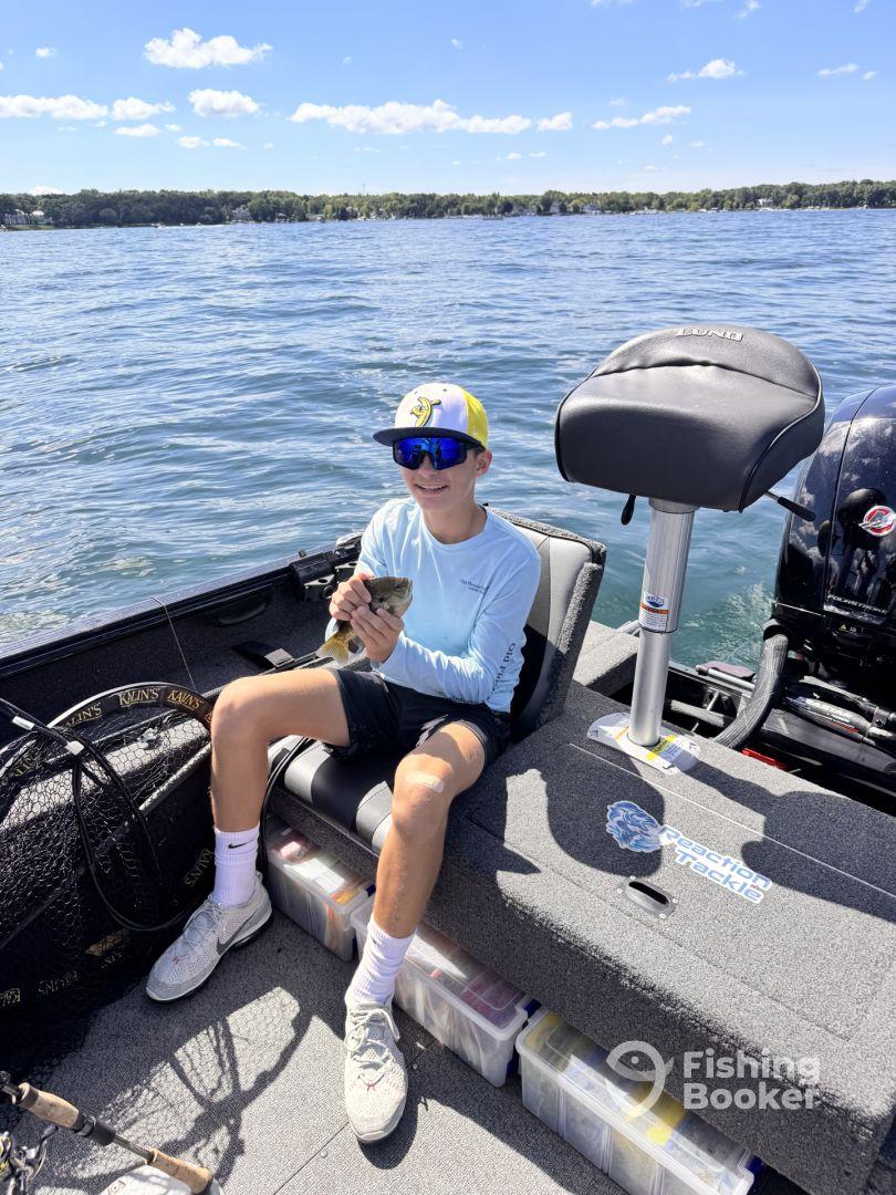 A young angler sitting on a fishing boat, proudly displaying a freshly caught fish while enjoying a sunny day on the water.