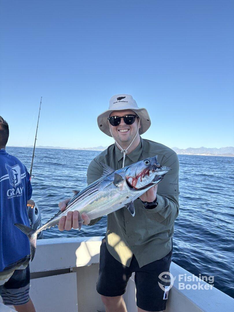 Angler proudly displaying a large fish while fishing on a boat in open waters.