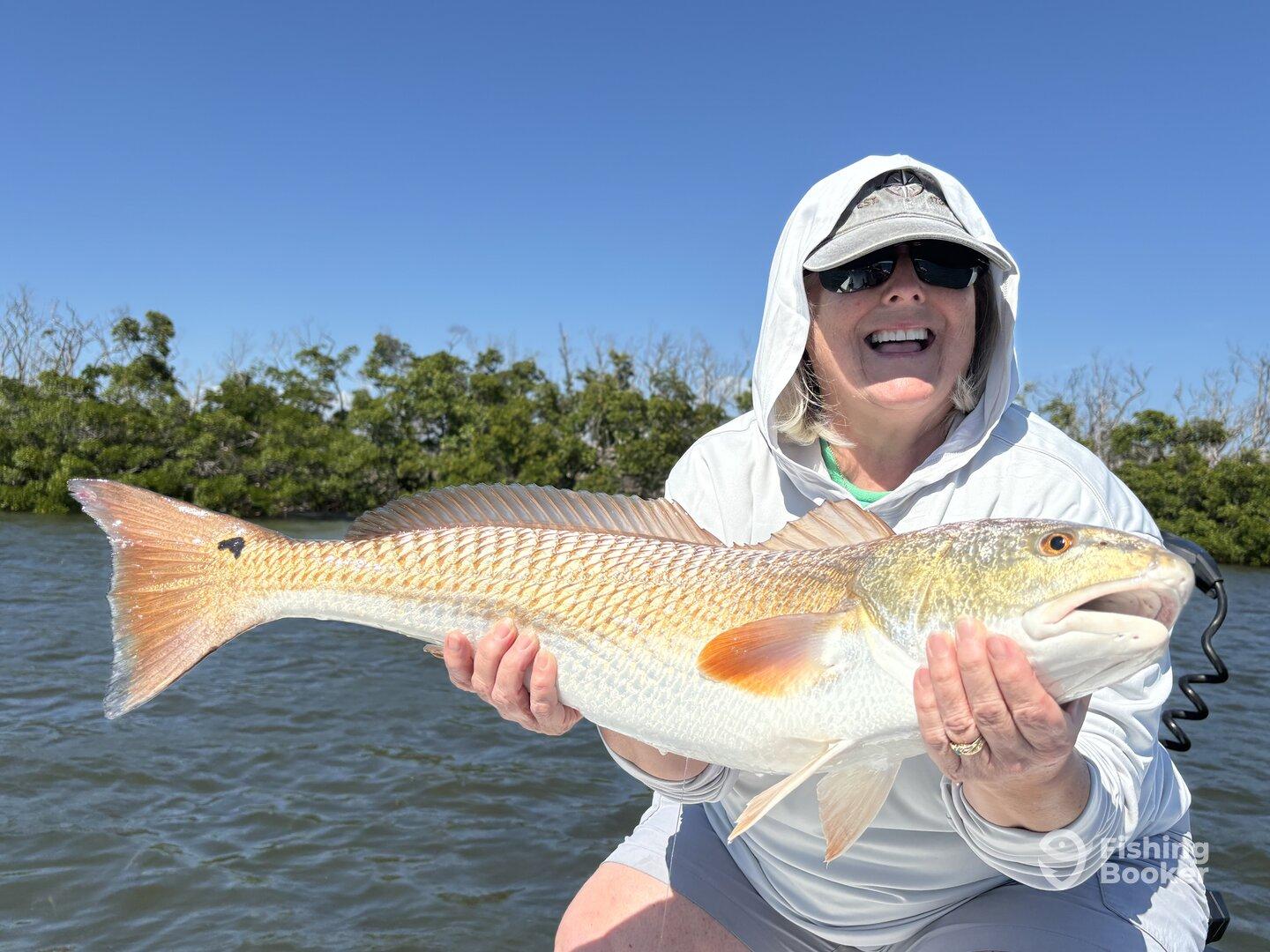 A proud angler holding a large Redfish while enjoying a sunny day on the water.