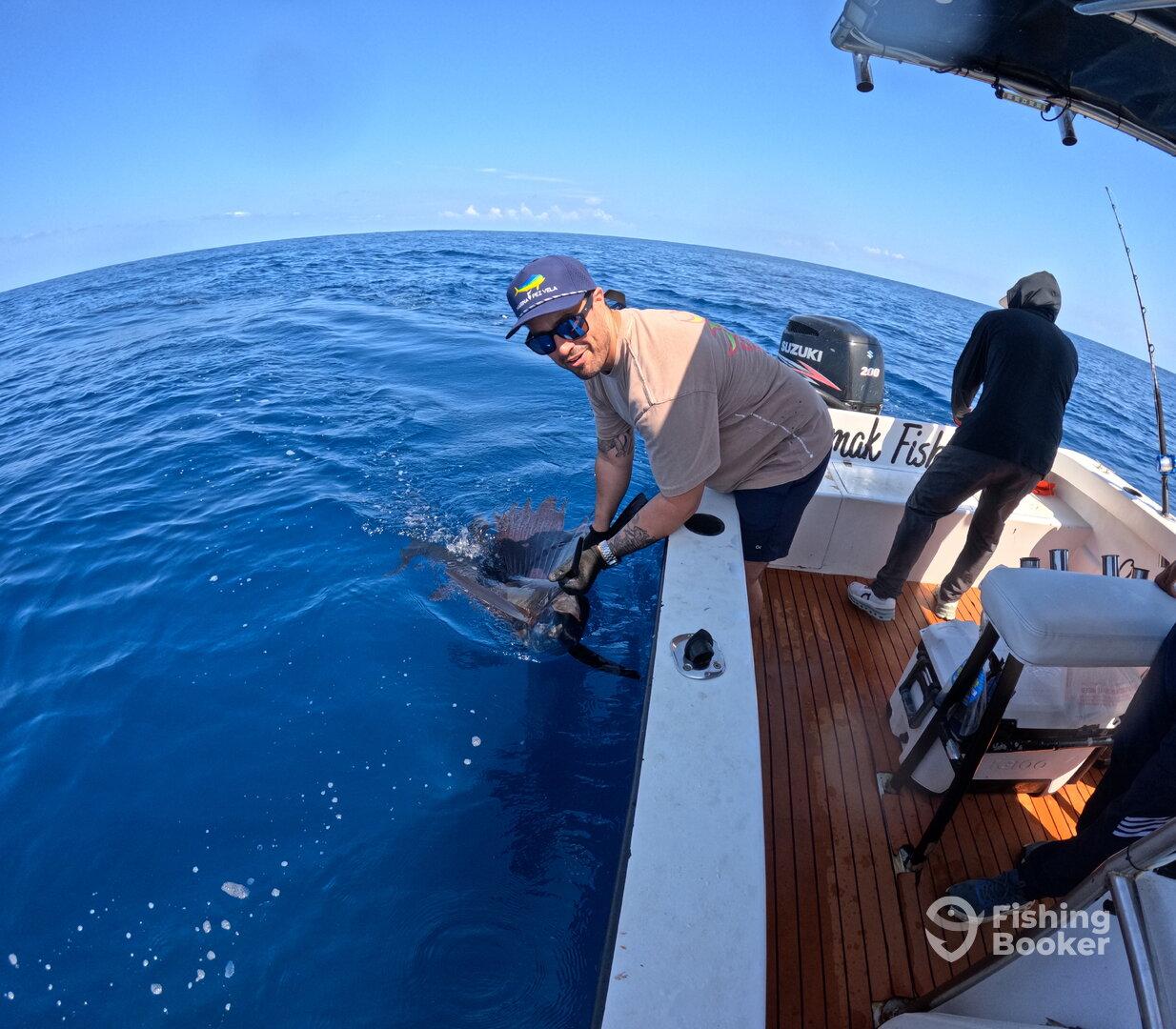 Angler actively reeling in a fish while fishing on a boat in open waters, showcasing the excitement of sport fishing.