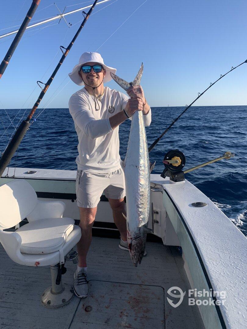 Angler proudly displaying a large Barracuda while fishing offshore, showcasing a successful day on the water.