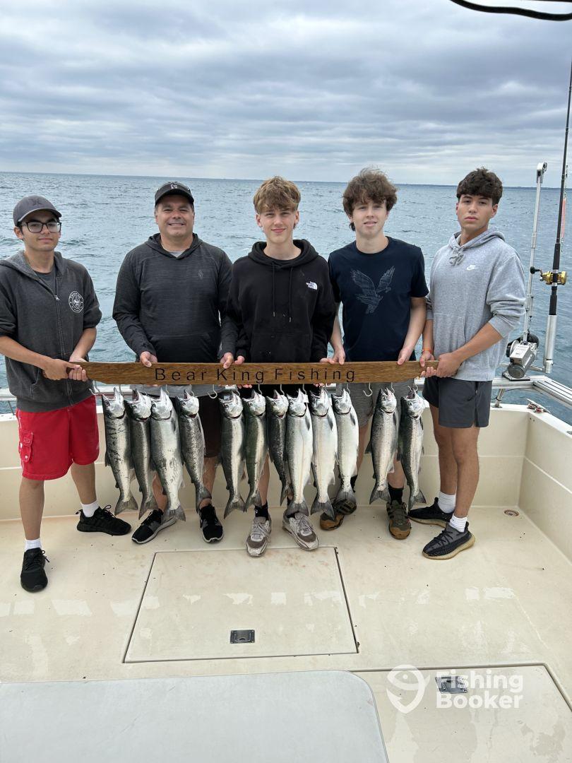 A group of young anglers proudly displaying their catch of salmon on a fishing charter, showcasing a successful day on the water.