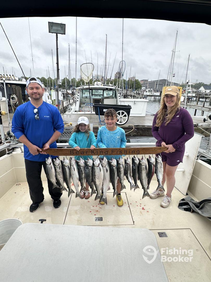 A family proudly displaying their catch of multiple fish on a fishing charter, showcasing a successful day on the water.