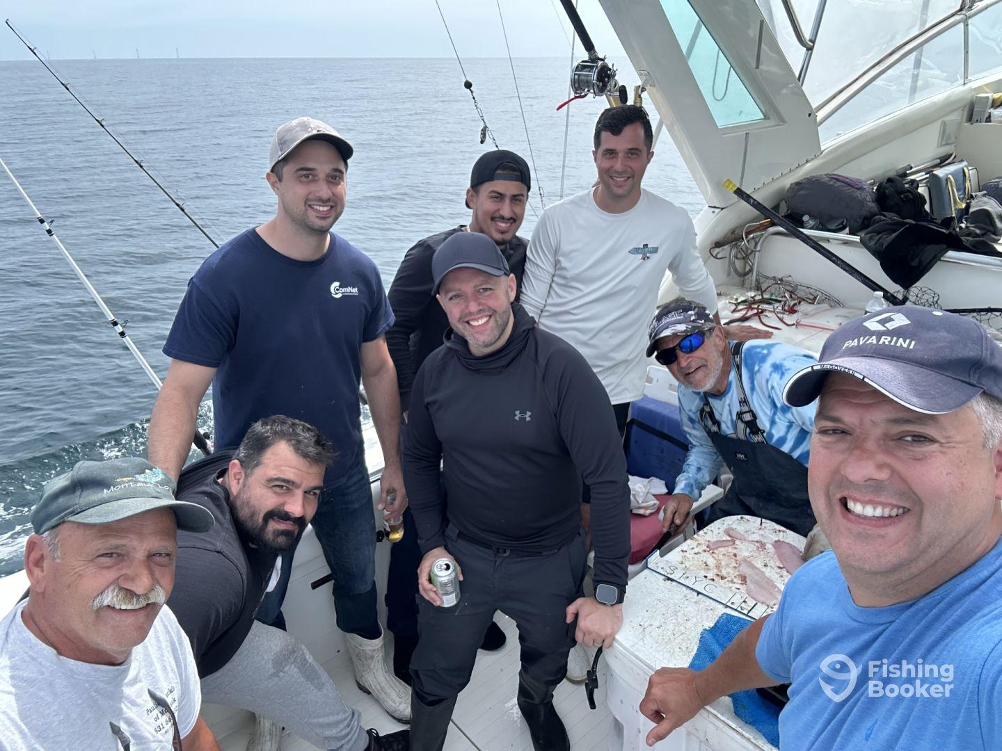 Group of anglers enjoying their time aboard a fishing charter, with visible fishing gear and a relaxed atmosphere.