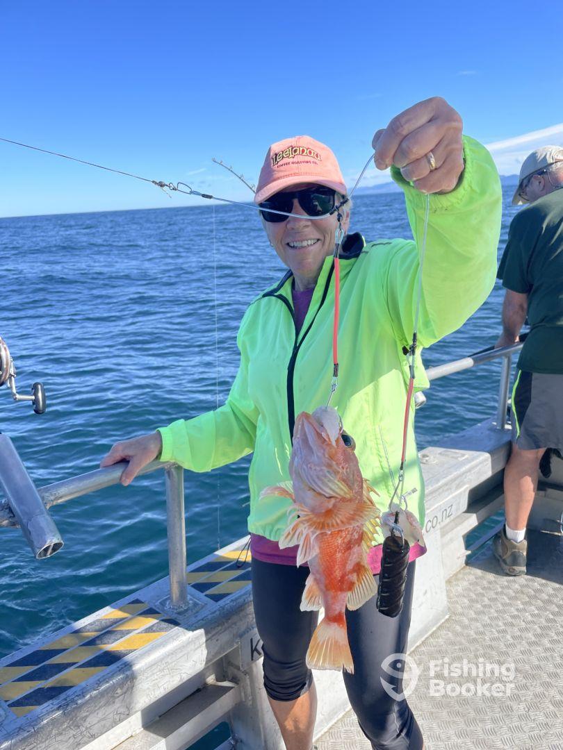 An angler proudly displaying a large Snapper while fishing on a charter boat in clear blue waters.